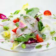 はじめのひと皿は四季の恵みたっぷりの前菜がお出迎え。カンパチなど旬の鮮魚のマリネと、瑞々しい野菜で季節感満載のサラダ。オリーブオイルとワインビネガー、バジルのソースが味わいをグッと引き締めてくれます。