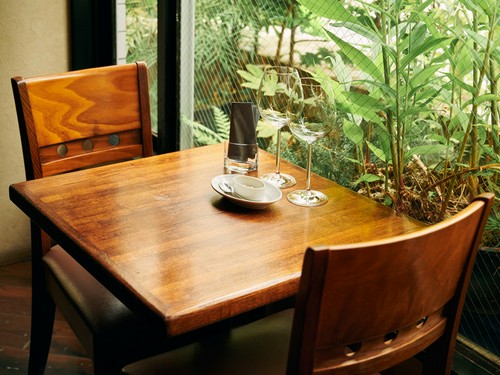 テーブル席の間合いも十分。シックな木のテーブルに緑が映える
