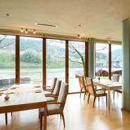 一面ガラス張りの大きな窓からは、ゆるやかな流れの川面や山々の景観を。お店の各壁面は絵画で彩られ、まるで美術館にいるような気分にさせてくれます。昼と夜とでは違った面持ちを覗かせるレストランです。