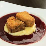 当店のスペシャリテである、牛ホホ肉の赤ワイン煮込みをパン粉をつけて揚げカツレツに仕上げました。カラッと揚がった衣とよく煮込まれた牛ホホのトロっとした食感の対比がたまりません。おすすめの赤ワインと是非！