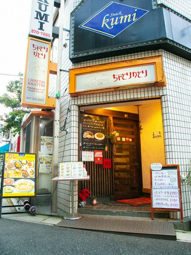 駅から線路沿いを東へ歩くと見つかる、赤い文字の看板が目印