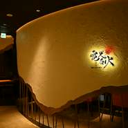 通常のお好み焼き店のイメージとは異なる、モダンで洗練された空間。店内に入ると、広島の牡蠣の殻が埋め込まれた白い壁が目を引きます。個室も完備され、さまざまな用途に合わせて利用可能。