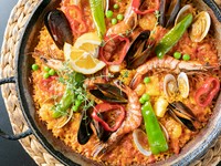 大鍋で炊き上げる名物料理は、S～Lの3サイズ。魚介のパエリアは、大小の海老に加え、アサリ、ムール貝、イカが入ってボリューム満点です。魚介の旨みにスペインのブイヨン・カルドやスパイスが合わさり絶品。