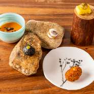 内容は仕入れなどより変わります。画像は左奥から時計回りに、冷製ガスパチョ、タラとじゃがいものコロッケ、うずらのクリームコロッケ、燻製ムール貝のピューレを乗せた自家製パン、焼き野菜を挟んだマカロン。