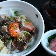 カウンター前で豪快に焼き上げるカツオと特製のタレ、濃厚な玉子が絡む絶品丼。小鉢、赤だし付き