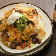 トルティーヤチップスにサルサ・チリコンカルネ・ワカモレなどをトッピングした、チーズが香るオーブン焼き。軽い食事としても人気です。スポーツ＆ビール＆ナチョスは、外国人のゲストに定番の組み合わせ。