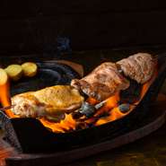 食材がゆっくりと炙られていき、香ばしい薫りが広がります。その迫力とパフォーマンスに、ゲストは声を上げずにはいられません。画像はお肉（『ミックス肉の短剣焼き』）ですが、さまざまな食材で楽しめます。