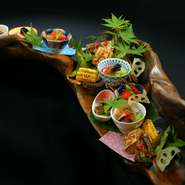 自然の姿が器としても美しい吉野川の流木。そこに多数の小鉢や食材を盛り合わせた前菜は店のNo.1メニュー。料理長自ら栽培した野菜をはじめ、季節の魚など、目利きの料理長が吟味した山海の幸が満載（予約限定）。