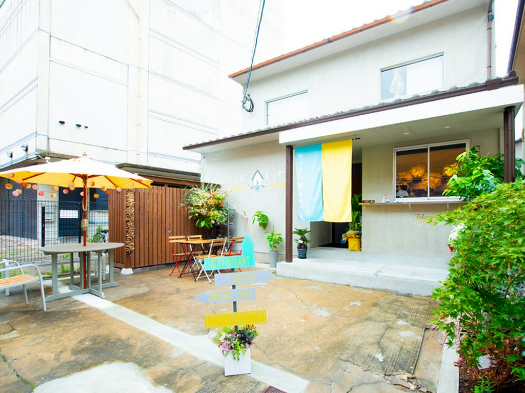 普通住宅のような一軒家に水色と黄色の暖簾と野天傘が目印