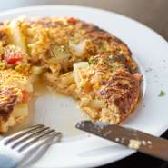 スペイン料理店で働いていた経験もある店主こだわりのオムレツはとろ～り半熟タイプ。中身は、卵と相性の良い玉ねぎ、じゃが芋、トマトです。オリジナルのガーリックマヨネーズの味付けで、ワインによく合います。