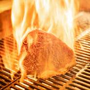 オープンキッチンで豪快に焼き上げる薪焼き肉『マキヤキ』がお店の自慢。1階の客席からは焼いているところを見ることができ、火が立ち上る臨場感あふれる演出に思わず目を奪われます。
