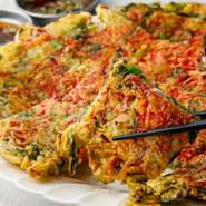 チヂミは韓国家庭の日常食。韓国料理店なら置いていない店はないほど定番ですが、こちらではニラ・ネギに加え、魚介類が入った『海鮮チヂミ』。歯ごたえサクサクのサクラエビも載っています。