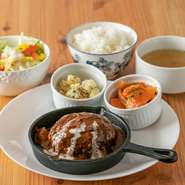 『チキンソテー』や『トマトとバジルの豚肉炒め』など、肉料理の日替わりランチ。人気の『煮込みハンバーグ』（写真）は、つなぎに麩を使ったヘルシー志向で肉汁たっぷり。デミグラスソースとの相性もバッチリです。