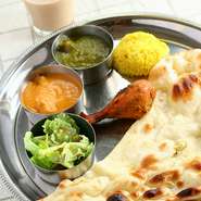 本場インドの食器「ターリー（銀大皿）」に、カレー2種類、ナン、サラダ、タンドリーチキンがのっています。
ドリンク付