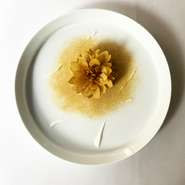 天竺牡丹（ダリア）を模した花は大根と菊花のジュースを飴細工の手法で極薄く焼いたもの。花びらとして一枚一枚組み上げ花の下にある味噌と乳酸で漬けたフォアグラとカボスゼリーとともにいただきます。ディナー限定