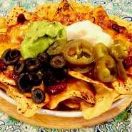 当店人気の本格派ナチョス。コーントルティーヤチップスにひき肉とキドニービーンズのソース。レッドチェダーチーズ、ワカモレ、サワークリーム、ハラペーニョ、ブラックオリーブをのせてオーブンで焼き上げます！