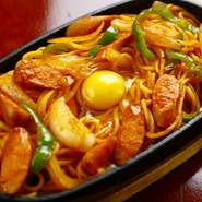 具材は、ウインナー、玉ネギ、ピーマンとシンプルにしています。最後にトッピングされた生卵が、鉄板の熱で半熟状に…。トロッとした卵と一緒に食べることで、味がまろやかになります。