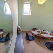 弧を描いた個室のカタチ合わせるように、円形の座卓と丸い座椅子が置かれています。絨毯が敷かれ、履き物を脱いで上がるタイプの半個室。子ども連れでの食事が気軽にできます。