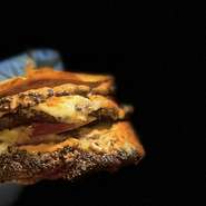 当店の名物ハンバーガーがリニューアルしました。さらに迫力満点で食べ応え抜群！当店に来たらまずこれは攻めて頂きたい1品。ジューシーで肉々しいごだわりのパティをご堪能下さいませ！