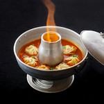 炎の演出が目を引く、熱々トマトスープにモモ（ネパールの蒸し餃子）を入れて提供いたします！ここでしか食べられない驚きのメニューをどうぞご堪能ください
