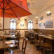 テラコッタタイルの床と白い壁、無垢材のテーブル。南イタリアの食堂さながらの空気感が漂う店内は明るい笑顔と活気があふれる空間です。おいしい食事とワインを片手にゆったりした昼下がりを過ごしてみてはいかが。