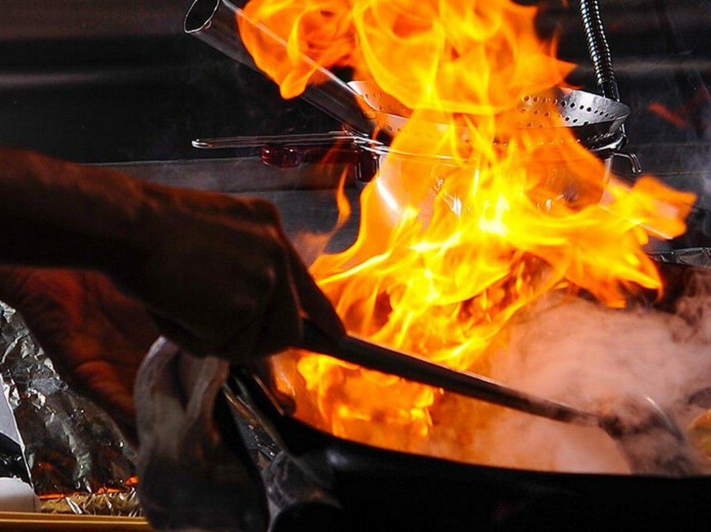 炎を巧みに操りながら、料理を完成させていく