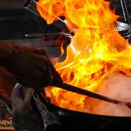 炎を巧みに操りながら、料理を完成させていく