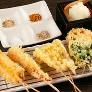 旬のおいしさを集結させた天ぷら。香り高い白しぼり胡麻油をブレンドして使用することで、カラッと仕上げています。雪塩・鯛塩など、季節に応じた4種類の塩を添えて。（画像左から、穴子・海老・鱚・菜の花・蓮根）
