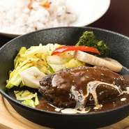 その日の朝に粗く挽いた新鮮な黒毛和牛をレアで焼いた肉肉しいハンバーグ。ペレットで焼きながらお召し上がり下さい。
M size：1080円（税込1188円）
L size：1280円（税込1408円）