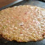 明太子の程良い辛み、もちの柔らかな食感、とろけるチーズのコクが一体となった一枚です。焼きながらヘラですくい上げるたびに素材の風味が絡み合い、味わいが深まります。