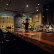 一枚板のカウンター席は、バーテンダーの華麗な技を臨める特等席。間接照明が照らし出す店内は、都会の喧噪を忘れ、明日からの鋭気も養えるような心地の良い空間です。