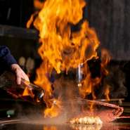 鉄板焼きだからこそ、ゲストが料理人のパフォーマンスを目の前で見ることができます。炎の大きさと迫力に思わず漏れる驚き感動の声。スピード感を伴う見事な動きに釘付けです。