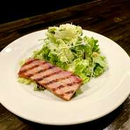 ジューシーな厚切りベーコンを添えたシーザーサラダ。シャキシャキのレタスと濃厚なドレッシングで、至福の一皿。






