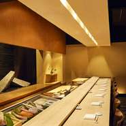 白木の一枚板の寿司カウンタ－で旬のにぎり寿司をはじめ、日本人ならではの和と洋の融合した料理が愉しめます。最大8名様まで収容可能な京都のおばんざいを思わせる優雅な和室でのデートやご接待などを演出します。