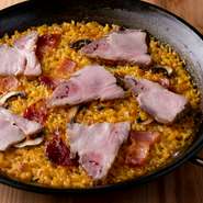 イベリコ豚ベーコンをたっぷり並べた、味わい豊かなパエリアです。どんぐりを食べて育つイベリコ豚は、脂に甘みがあり口の中でとろける食感。そんな肉の旨みが浸み込んだ、お米のおいしさがたまらない逸品です。