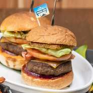 重さ180gの粗挽きパテを直径14cmのバンズではさんだ超BIGサイズのハンバーガーです。色とりどりの野菜に焼きパイナップル、チーズやベーコンが相まって食べごたえ抜群。出来立てアツアツをかぶりつきたい一品です。