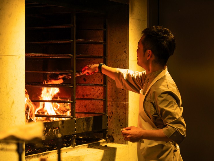 薪焼きの炎が見えるオープンキッチンで心躍る食体験を供する
