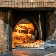 このお店の名物は、オーダーメイドの薪窯で焼くナポリタイプのピッツァ。イタリア産と国内産の小麦粉を独自にブレンドし、具材と小麦の旨みを引き出しています。30種類から好みの一枚を選ぶのも楽しみの一つ。