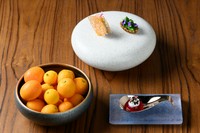 コースの開幕には季節のアミューズが登場。写真は春～夏の一例で、フォアグラのテリーヌ、アスパラガスと貝のタルトなど。金柑が入った器には或るスターターが隠れており、ゲストがそれを見つける趣向が楽しい！
