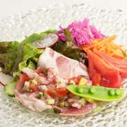 生ハムとフレッシュな野菜の盛り合わせ。生ハムは、飼料にマロングラッセの原料となる栗を与え、健康的に育てられた栗豚を使用。あえてメインをオーダーせず、こちらの一皿＋パンをワインと楽しむのもオススメです。