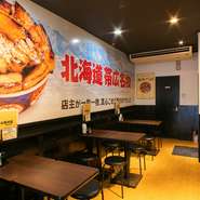 4名がけのテーブル席と4～6名で利用できる座敷席が並ぶ店内。壁に大きく書かれたメニューが、大衆食堂のような雰囲気を醸し出しています。たくさんの人を魅了する『豚丼』を囲み、楽しい時間を過ごしてはいかが。