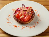 パスカードの中には、みじん切りにしたフルーツトマトをエシャロットとペドロヒメネスのビネガー、オイルで和えたものを。トマトのコンソメゼリーを上にのせて、周りにはトマトパウダーをあしらっています。