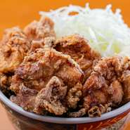 醤油ベースにショウガやニンニクなどの薬味を効かせた秘伝のタレに一晩漬け込んだ鶏肉を、みんな大好きなから揚げに。たっぷりの千切りキャベツ、マヨネーズとともにごはんに乗せた丼は、老若男女に愛される味です。