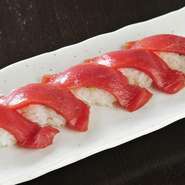 本鮪の持つ魅力が高められ、上質なおいしさに満たされる大人気メニューです。赤身本来のみずみずしさや色合いを残すため、秘伝のタレに漬け込む時間なども細かに調整。店主渾身の漬け握りです。