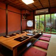 最大8人まで座れる掘りごたつの座敷席は、濃い赤の内壁がオシャレで、特別感が漂います。趣のある庭が窓から楽しめる点も魅力。間仕切りをすれば2組まで入室可能なので、気になる方はお早めにお問合せを。