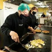 厳選素材とオリジナルレシピでつくる『お好み焼き』は、出来立てアツアツをゲストの元へ届けます。熟練の技で焼き上げる一品は外はカリッと、中はふわっと。忘れられないおいしさがリピーターを増やしています。