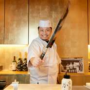 “カウンターの鮨”が初めての方でも、肩ひじ張らず「笑顔で食べてほしい」と蛎田氏は語ります。まるで日本刀のような大振りの鮪切り包丁を見せてくれて記念撮影。豊洲での仕入れや旬の魚の話にも花が咲きます。