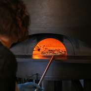 店内には、どの席からも楽しめる薪窯が設置されています。本格的ナポリピッツァを提供するために必要不可欠な、シェフこだわりの薪窯。焼きたてのアツアツを堪能できます。