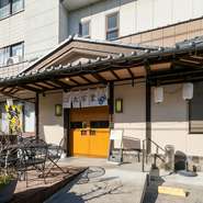 JR宇都宮線氏家駅のすぐ近くに構える【久万皇】。店へと続くアプローチはスロープになっており、車いすやベビーカーの利用もOK。店舗前にはテラス席や喫煙スペースも用意され、全てのゲストをあたたかく迎えます。