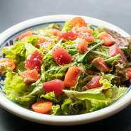 たっぷりのフレッシュ野菜を彩るのは、地元の魚屋さんから届く色とりどりの海の幸。鮪やサーモンなどその日のオススメ鮮魚が盛り込まれ、醤油ベースの和風ドレッシングでいただきます。